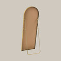 back of a cheval mirror with a gold frame, shown on a beige background