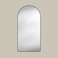 Arched leaner mirror with black frame on a beige wall