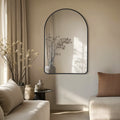 Elegant black-framed arched mirror, styled in a serene neutral setting to reflect natural light and create a sophisticated focal point.