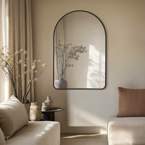 Elegant black-framed arched mirror, styled in a serene neutral setting to reflect natural light and create a sophisticated focal point.
