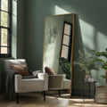 Contemporary gold leaner mirror with a slim frame, styled beside soft furnishings and natural greenery for a calm modern look.