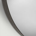 Detailed close-up of a modern mirror frame showcasing subtle wood texture, curved form and sophisticated dark tones.