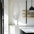 Slim oval mirror displayed in a bright modern kitchen, bringing soft curves, light and minimalist appeal to the space.