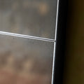 Close-up detail of an antiqued panel wall mirror with black metal framing and distressed vintage-style glass texture