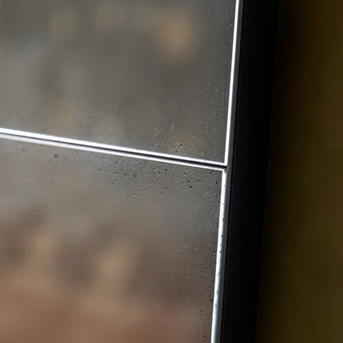 Close-up detail of an antiqued panel wall mirror with black metal framing and distressed vintage-style glass texture