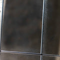 Close-up of a distressed windowpane mirror featuring textured antiqued glass and dark metal framing.