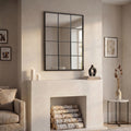 Large rectangular windowpane wall mirror with a black metal grid frame displayed above a minimalist fireplace in a bright contemporary living room.