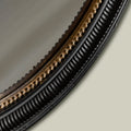 Close-up of a textured black mirror frame featuring ribbed detailing, warm metallic accents and decorative beaded trim.