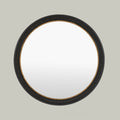 Round wall mirror with a textured black frame and warm metallic detailing.
