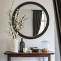 Decorative circular mirror styled above a wooden console, bringing sculptural texture, reflective light and sophisticated contrast to the space.
