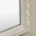 Detailed view of a distressed silver mirror frame with decorative carved detailing, antique-inspired texture and subtle bead trim.