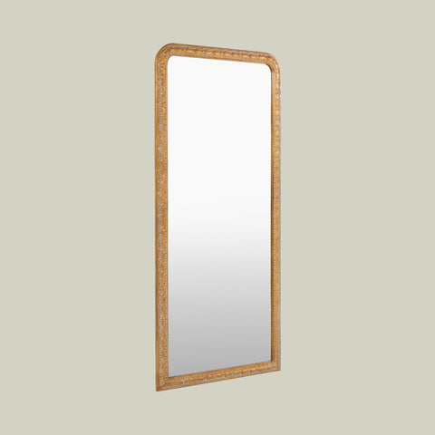 Elegant arched leaner mirror with a decorative gold frame, highlighting intricate carved patterns and a refined traditional finish.