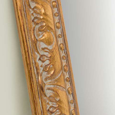 Close-up detail of an ornate gold mirror frame featuring intricate carved scrollwork, raised beading and antique-inspired texture.