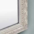 Close-up detail of a distressed cream mirror frame featuring ornate carved detailing, subtle speckled texture, raised beading and antique-inspired edging.