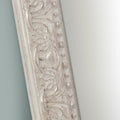 Decorative mirror frame detail with a distressed cream finish, refined carved pattern, raised beading and antique-style accents.