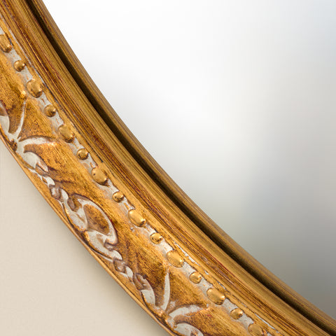 Decorative mirror frame detail featuring intricate gold scrollwork, raised bead trim and a softly antiqued finish.