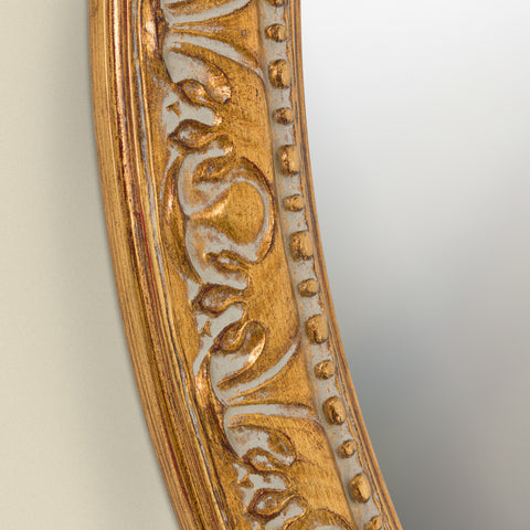 Detailed close-up of a decorative gold mirror frame showcasing embossed scroll detailing, beaded edging and vintage-inspired character.