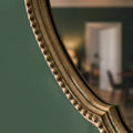 Ornate mirror frame featuring raised beaded detailing and softly aged texture.